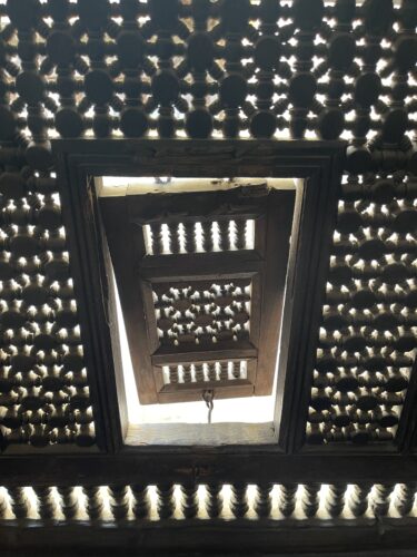 Patterned wood turnings framing a small closed window
